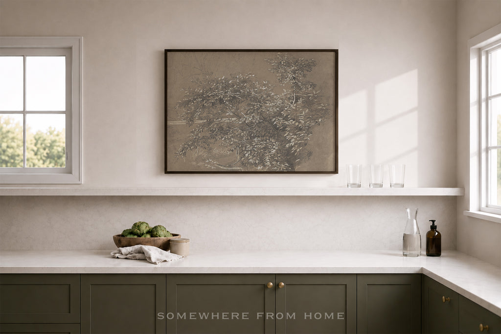 A framed botanical art print hangs on a light beige wall above a white shelf in a modern kitchen setting. The print features delicate, sketch-like tree branches in muted brown and gray tones.