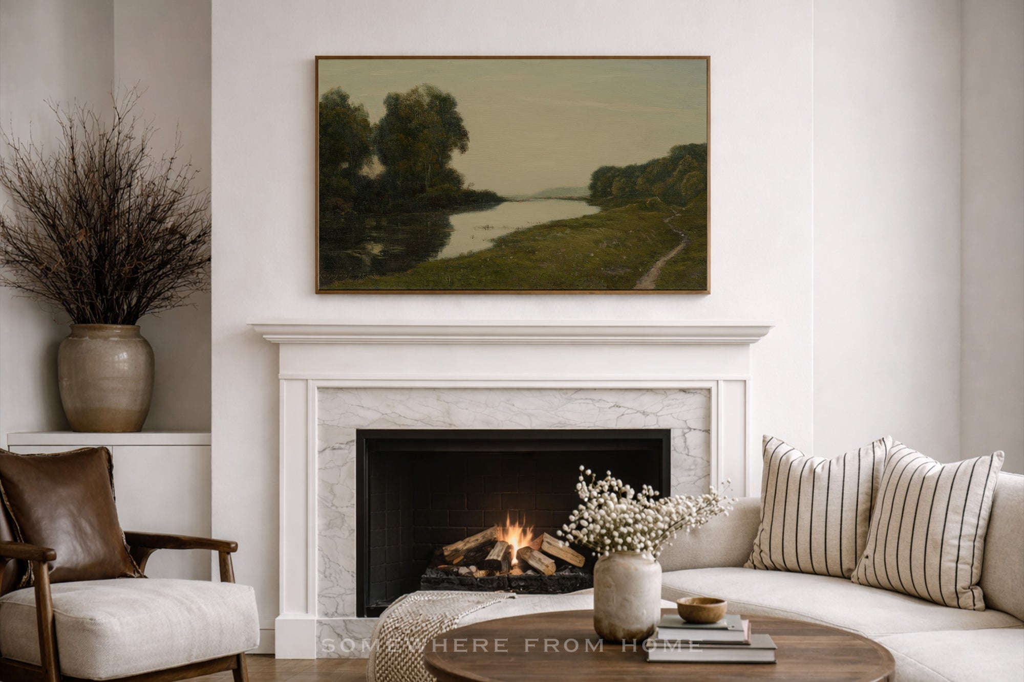 Living room with a fireplace, sofa, and large oversized muted landscape art print