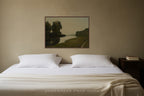 Bedroom with a bed, nightstand, and wall art of a landscape painting with river and trees with muted green