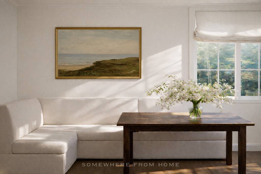 Dining room with white L Shaped banquette , wooden dining table, and framed green and blue landscape painting.