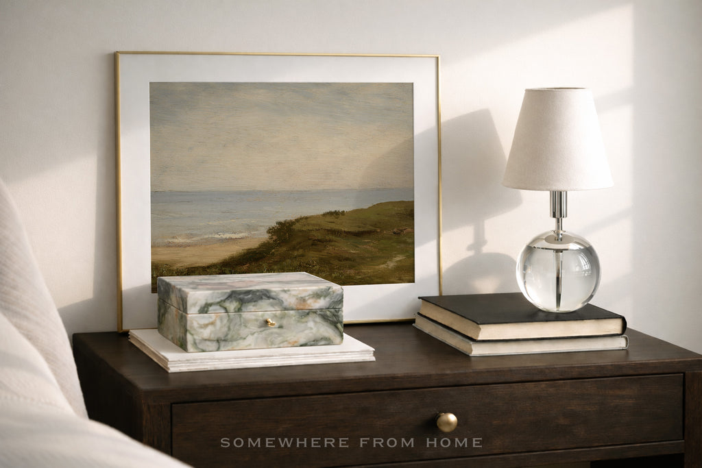Framed artwork, lamp, and decorative items on a wooden nightstand from 'Somewhere from Home' .