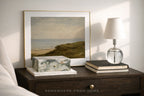Framed artwork, lamp, and decorative items on a wooden nightstand from 'Somewhere from Home' .