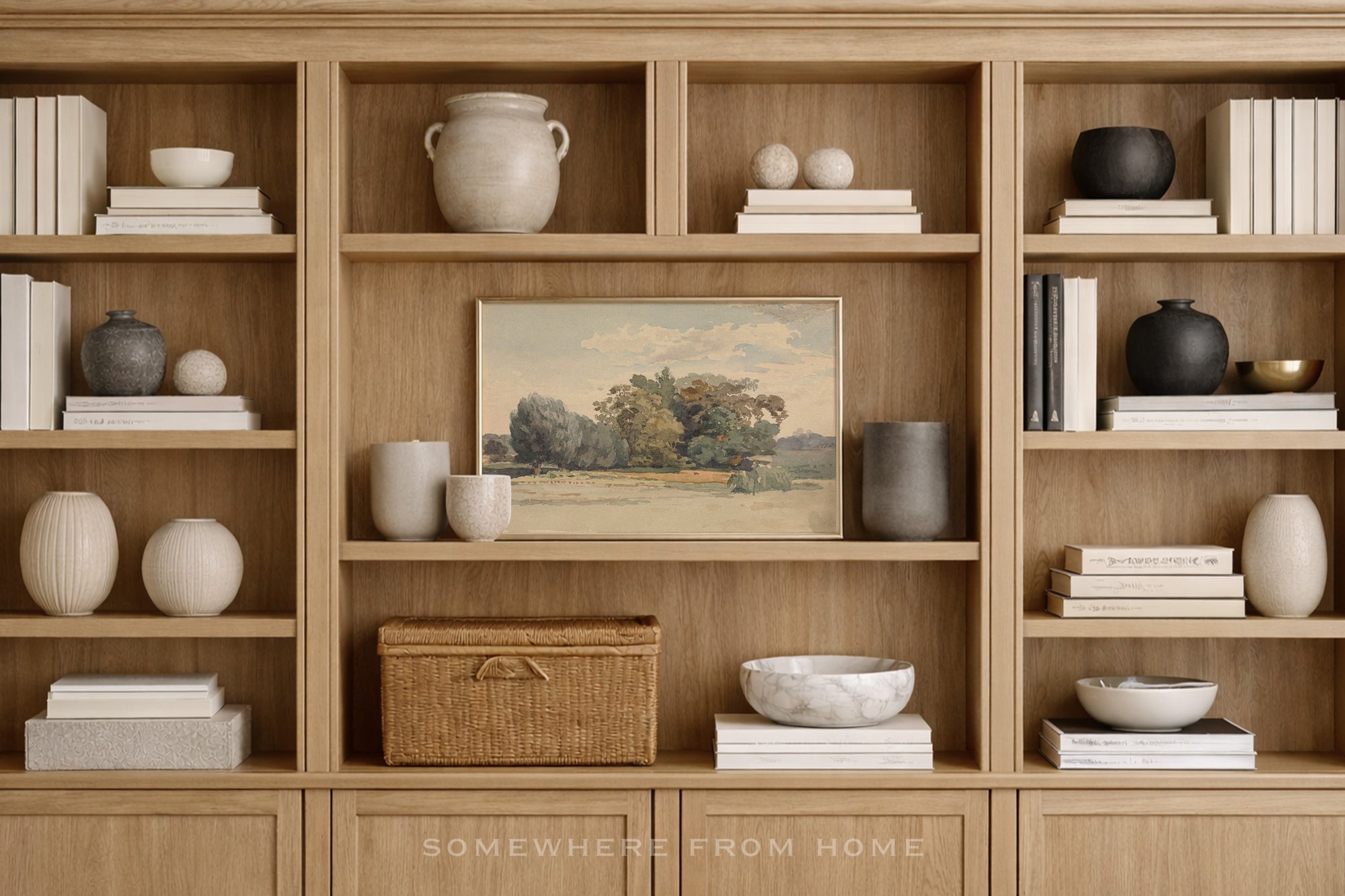A styled interior scene showing a light wood built-in bookshelf filled with books, ceramic vases, bowls, and a framed landscape painting. The text 'SOMEWHERE FROM HOME' appears at the bottom.