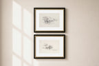 Two framed botanical art prints with black frames and gold inner trim, hanging vertically on a beige wall with soft window shadow light.