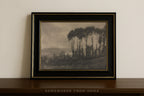 A framed landscape art print featuring a scene of tall trees and distant hills, presented in a black frame with gold trim on a dark wooden shelf against a light beige wall.
