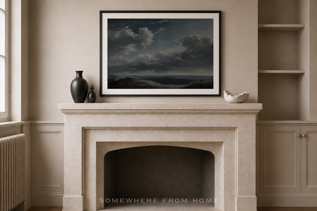 A framed landscape art print depicting a stormy sea under a dark cloudy sky, displayed on a beige stone fireplace mantel in a classic room setting.
