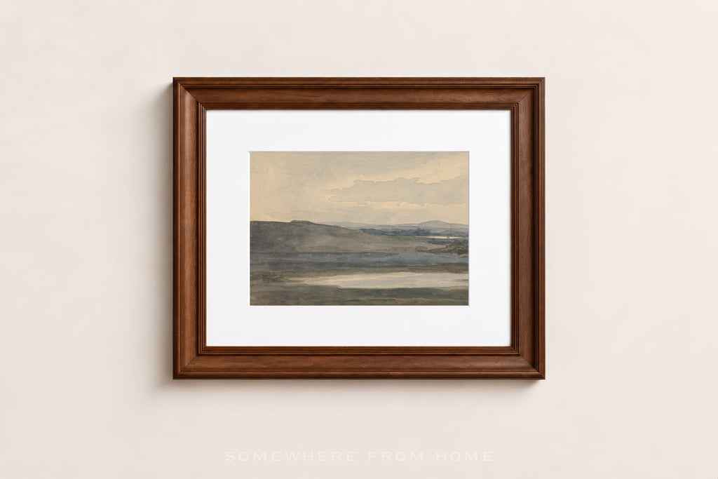 A framed landscape art print with a white mat and a dark brown wooden frame, hanging on a light beige wall.