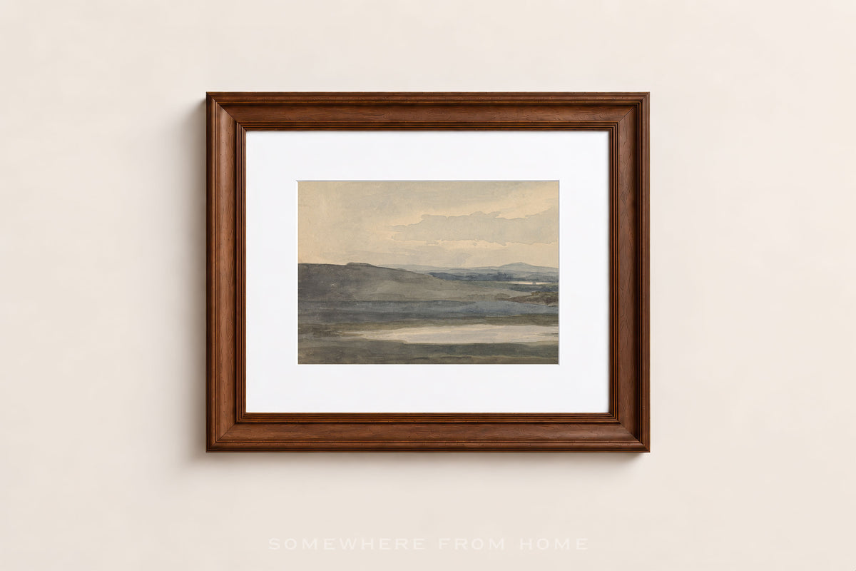 A framed landscape art print with a white mat and a dark brown wooden frame, hanging on a light beige wall.