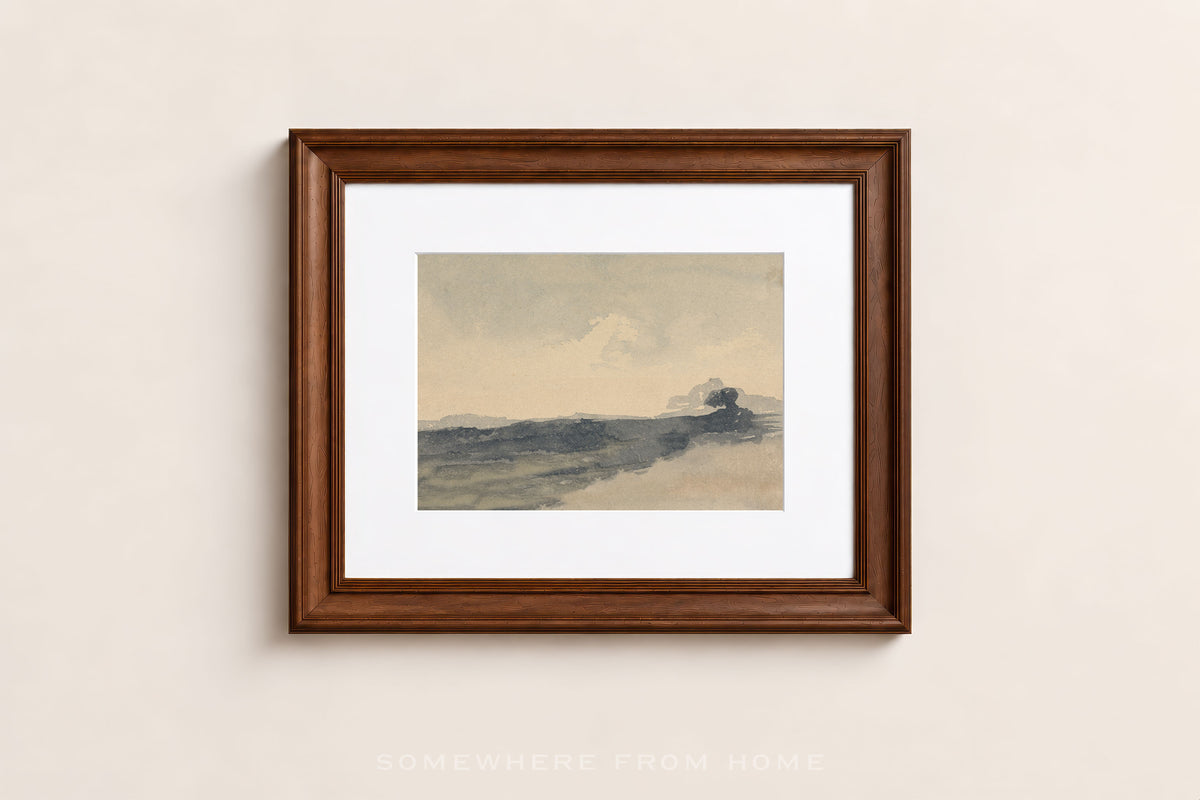 A framed landscape art print with a dark brown wooden frame and white mat, hanging on a light beige wall.