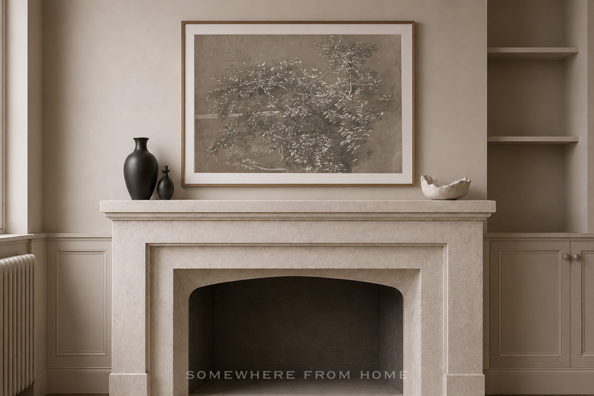 A framed sepia-toned botanical art print hangs on a beige wall above a stone fireplace mantel, styled with dark ceramic vases and a small white bowl. Built-in shelving is visible on the right.