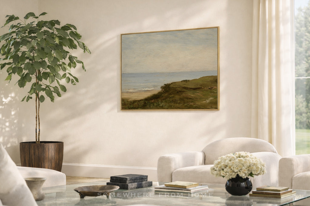 Living room with a painting of a green and blue coastal landscape, a plant, and a white sofa.