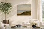 Living room with a painting of a green and blue coastal landscape, a plant, and a white sofa.