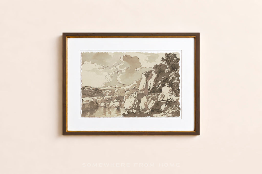 A framed art print featuring a sepia-toned landscape sketch with mountains, trees, and water, displayed on a light beige wall.