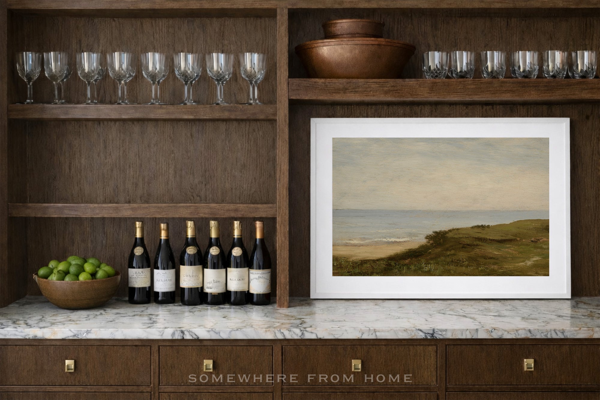 framed landscape painting, wine glasses, and a bowl of limes.
