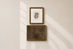 Two framed wall art pieces hanging vertically on a warm beige wall, with soft diagonal sunlight casting shadows across the scene.