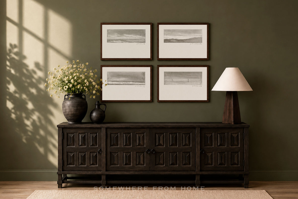 A dark wood console cabinet in a styled room setting, decorated with a vase of flowers, a table lamp, and four framed black and white landscape prints on an olive green wall.