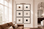 Six framed black and white art prints arranged in a 2x3 grid on a white wall in a bright, modern living room with a brown sofa and large windows.