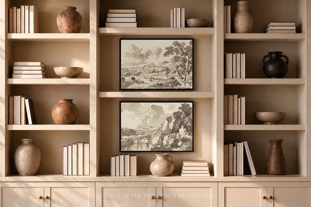A symmetrical beige built-in bookshelf with two framed sepia landscape prints centered on the middle shelves, surrounded by books, ceramic vases, and bowls.