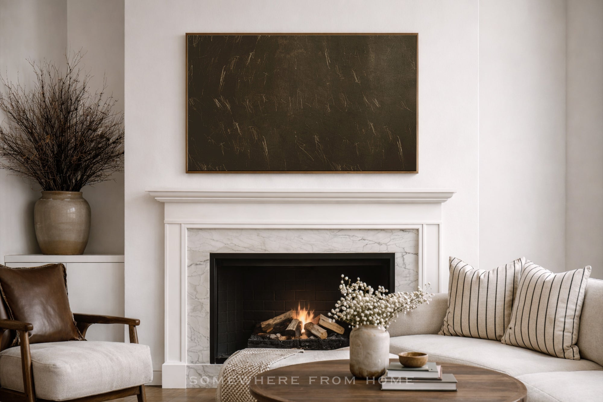 A large rectangular dark brown textured wall art piece hangs above a white marble fireplace in a styled living room with a sofa, striped pillows, and a coffee table.