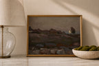 A framed landscape painting with a gold frame, styled on a marble surface next to a table lamp and a bowl of green moss, under warm natural light.