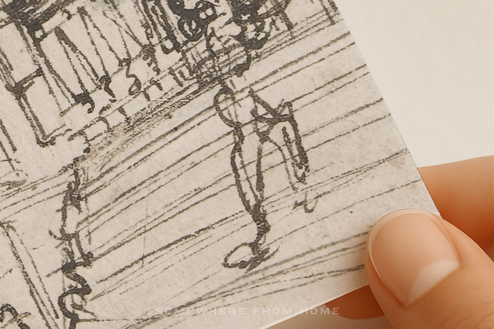 A close-up of a hand holding a small square piece of textured paper featuring a black ink sketch of a person walking, with a faint 'FROM HOME' watermark near the bottom.