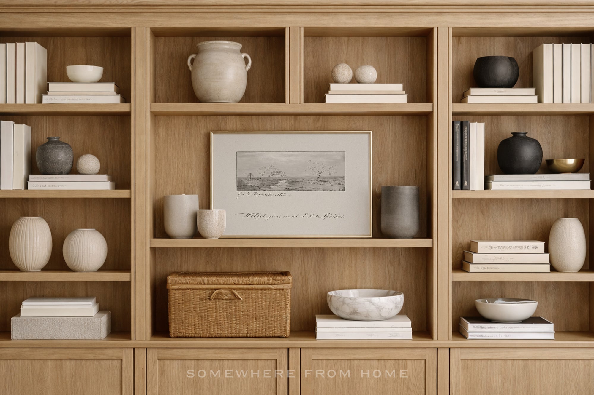 A styled interior scene showing a large light wood built-in bookcase filled with books, ceramic vases, bowls, a woven basket, and a framed monochrome print. The text 'SOMEWHERE FROM HOME' appears at the bottom.