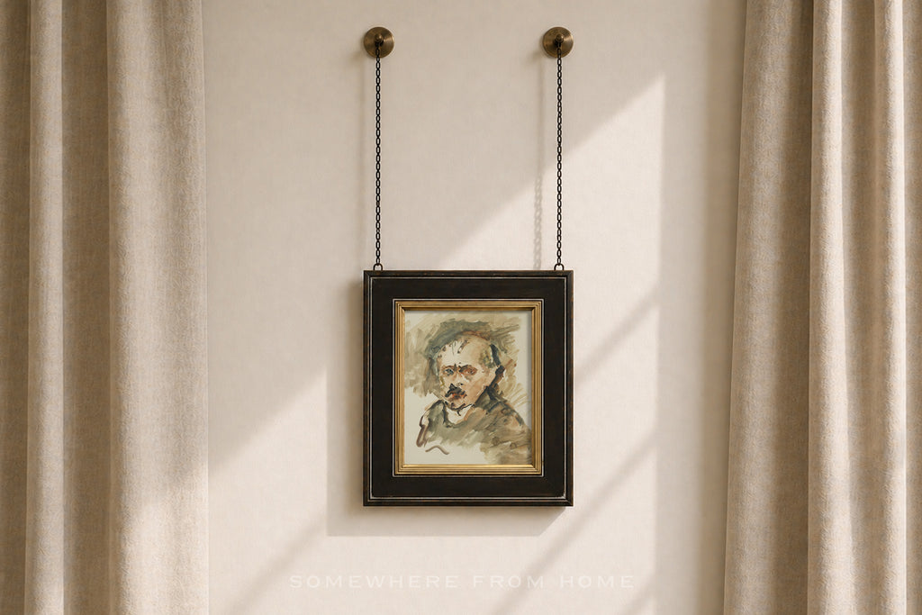 A framed portrait painting of a man with a mustache, hanging from two chains on a beige wall between beige curtains.