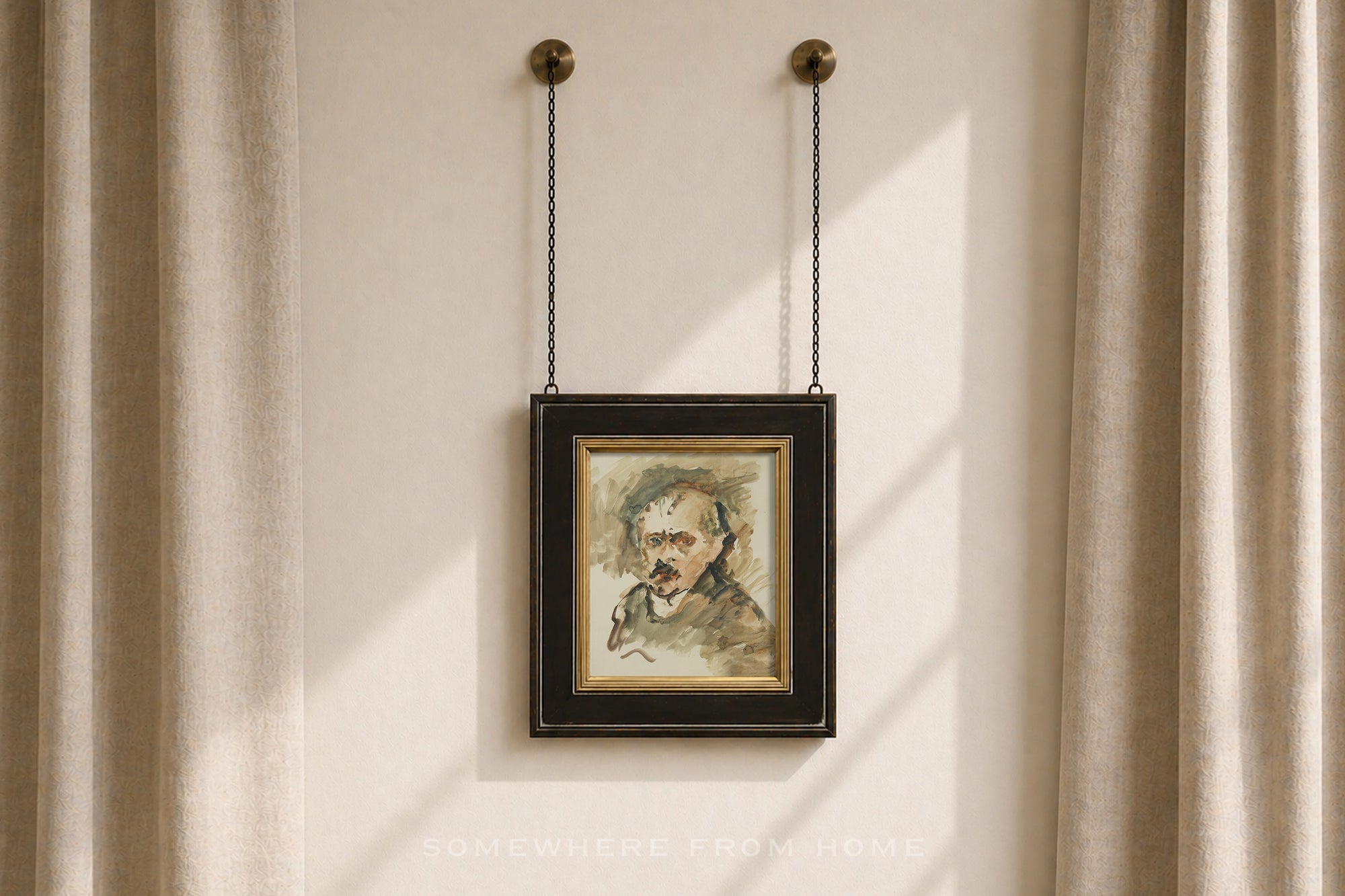 A framed portrait painting of a man with a mustache, hanging from two chains on a beige wall between beige curtains.